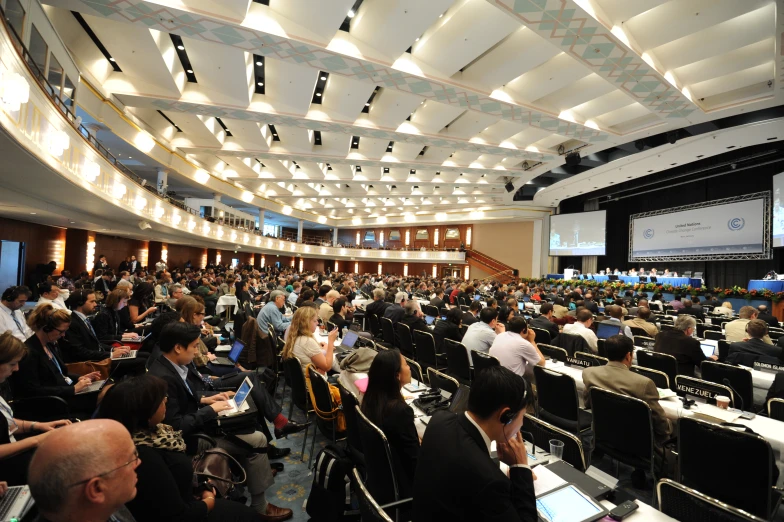 a large conference room filled with people listening to speakers