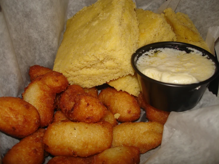 there are some fried food and a dipping sauce in a black cup