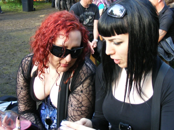 two women looking at soing while sitting in a field