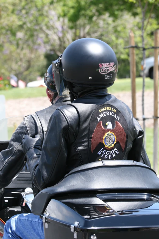 man riding on back of motorcycle wearing jacket and helmet