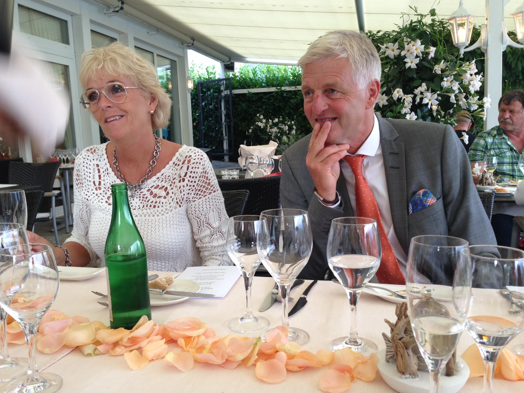 two people sitting at a table with glasses and wine in front of them