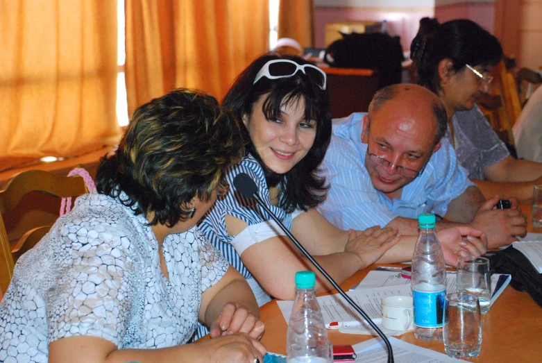 several people sitting around a table holding water bottles