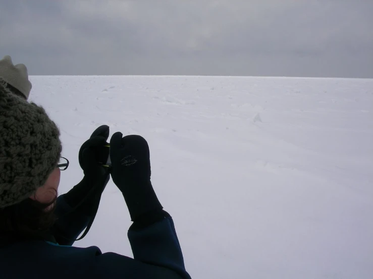 a man in a hat and gloves stands in snow