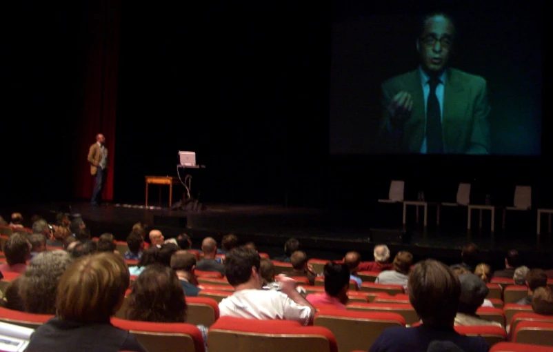 there is a man standing in front of an audience at a lecture