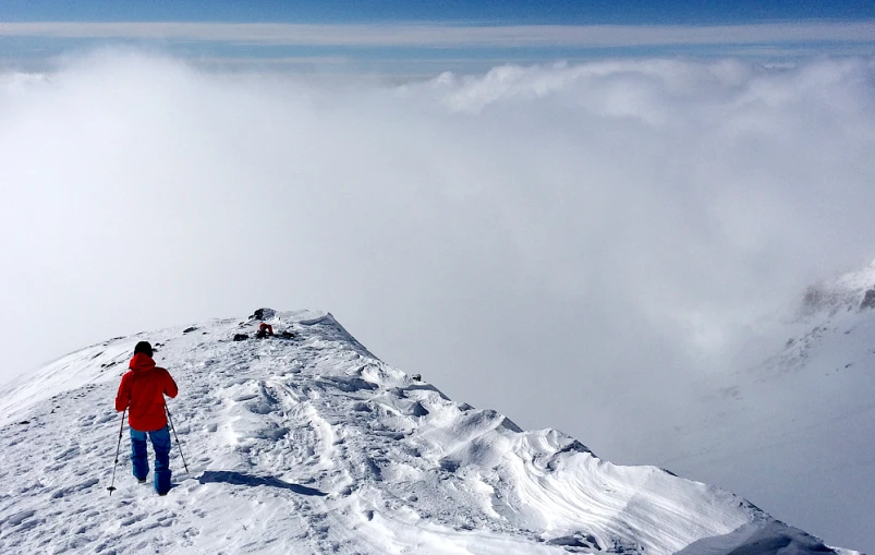 a man stands on top of a mountain, overlooking clouds