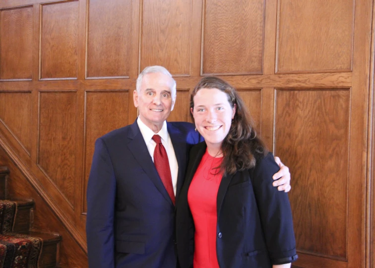 two people standing next to each other near some wooden walls