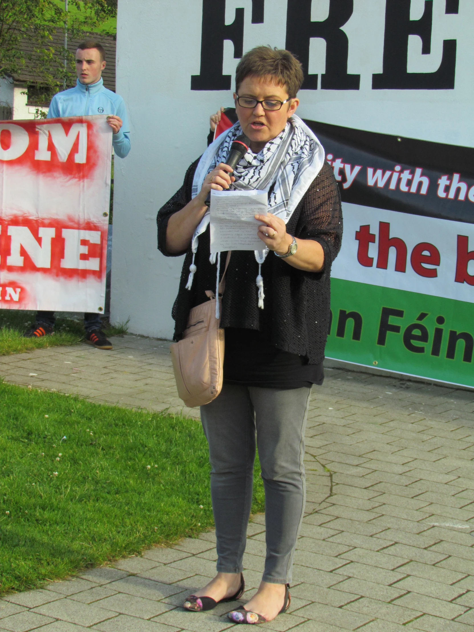 a woman stands in front of a political sign