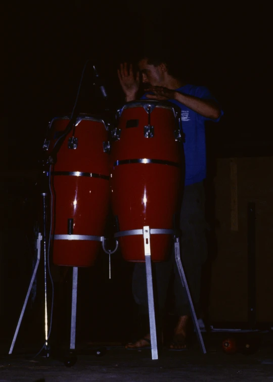 a man stands between three red drums