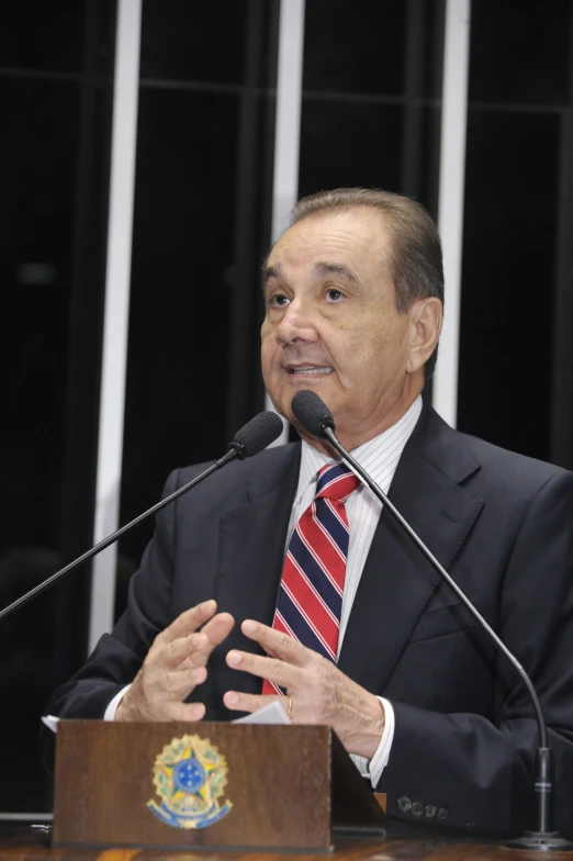 a man in suit and tie speaking from a podium