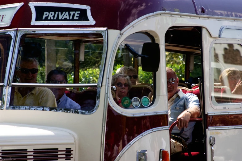 two old fashioned buses with people driving on the side of it