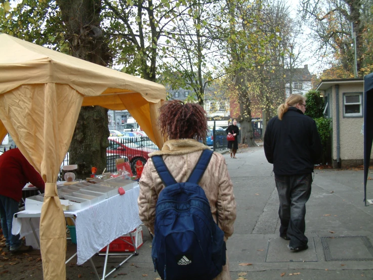 a woman with backpack is walking past a tent