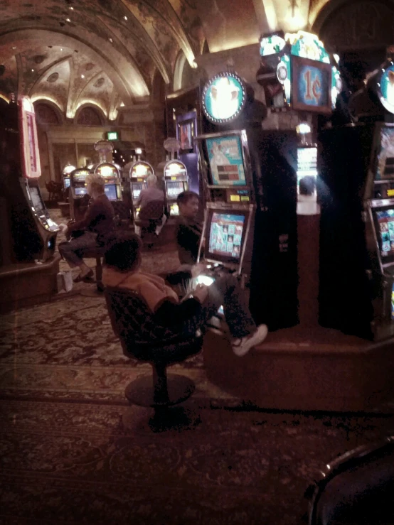 several men sit inside slot machines in an indoor casino