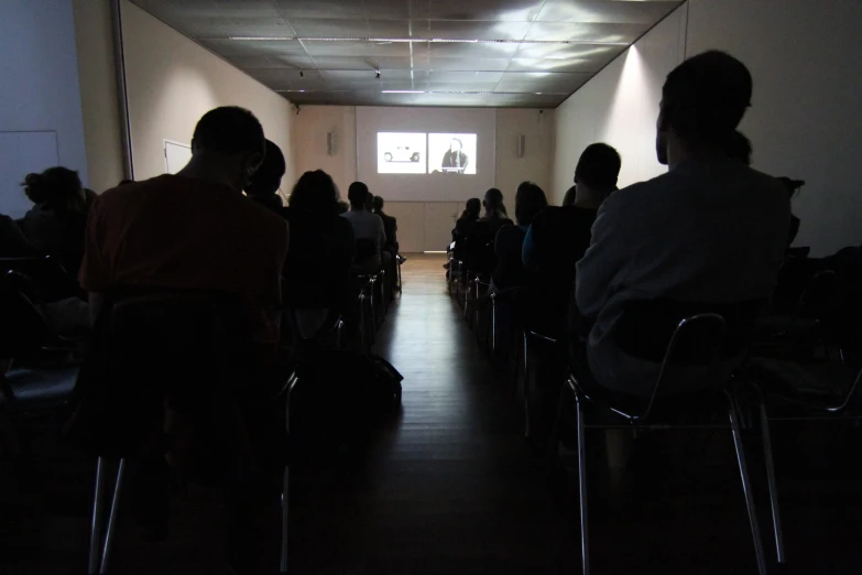 people seated and standing in an empty room