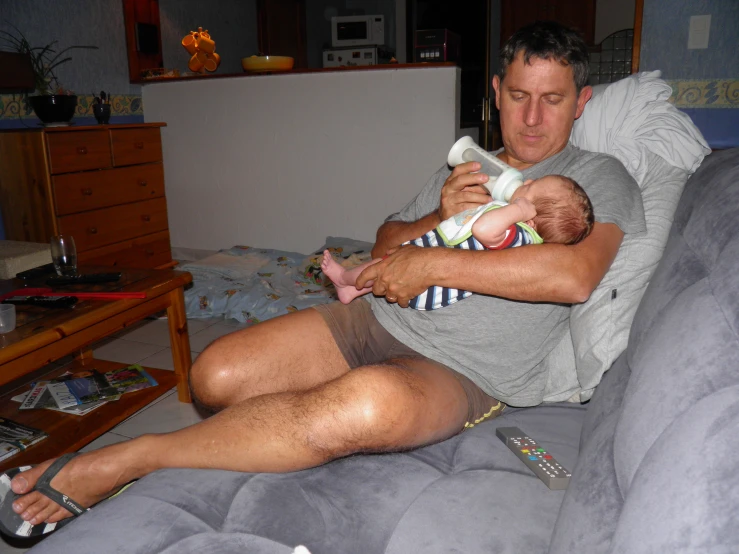 a man sitting on top of a couch holding a baby