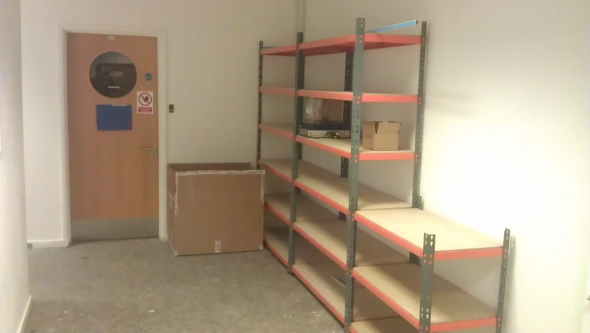 an empty room with a bookcase and boxes on the floor