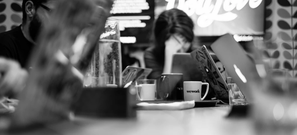 two people in a cafe looking at their laptops