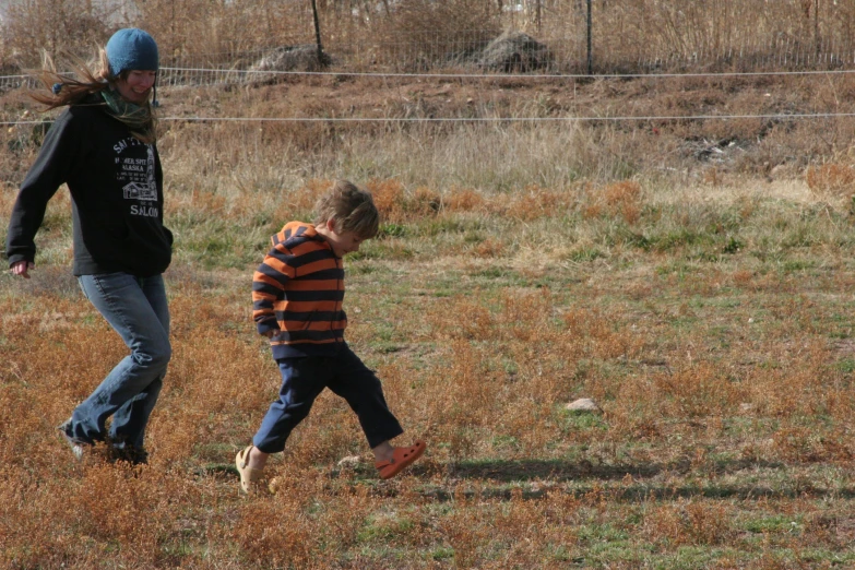 a woman in a blue hat and a little boy in the field