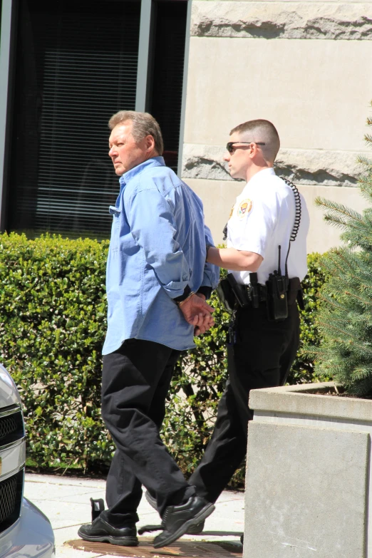 two men in police uniforms walking on sidewalk