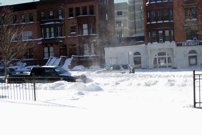 a black truck is parked in the snow near many buildings