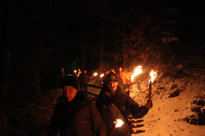 people stand in front of the bonfires on a snowy hill