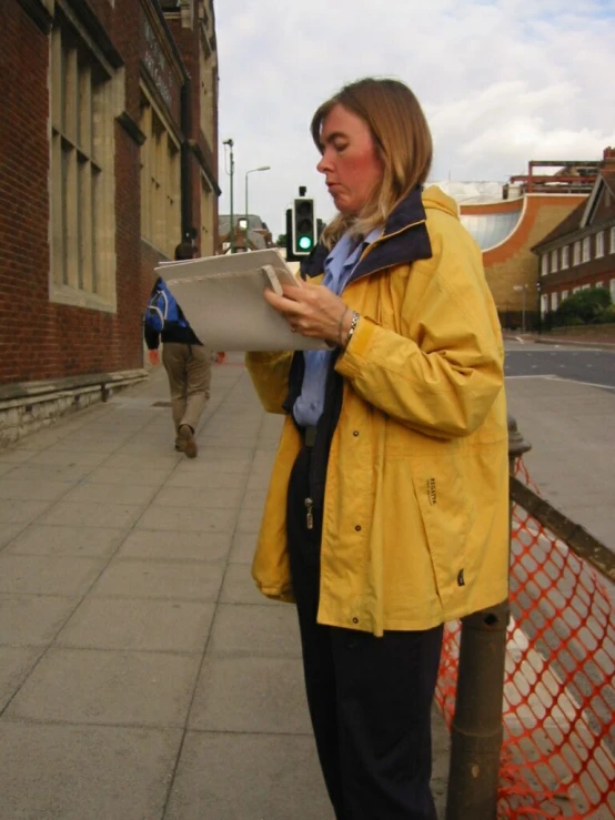 a lady is looking at some papers on the sidewalk