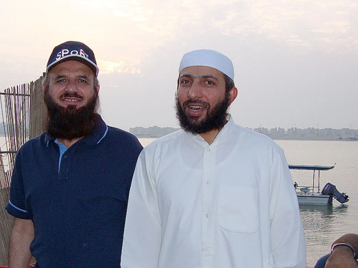 two men smiling in front of a body of water