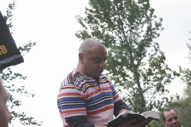 a young man is looking at a book outside