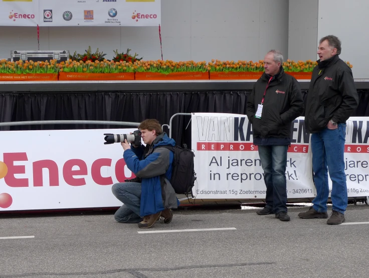 people standing on the street and a person sitting on the ground holding a camera