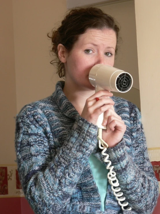 the woman is using a large blow dryer on her head