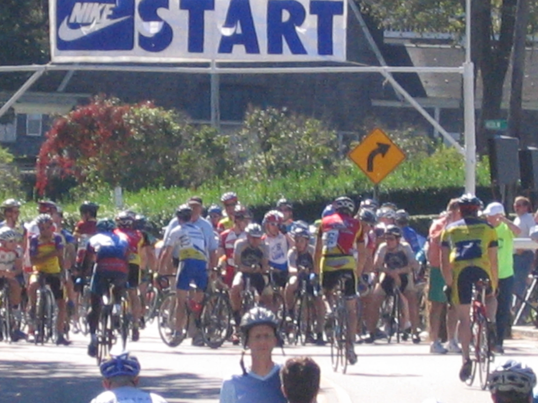 people are riding their bikes on the street near a start sign