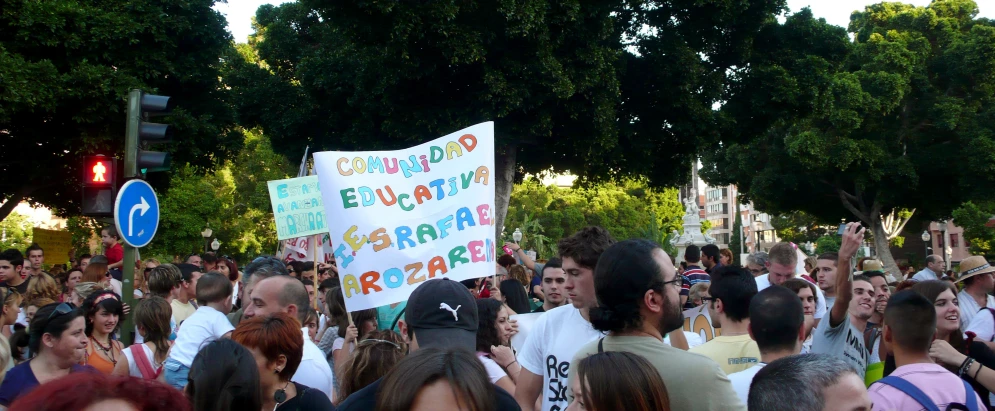 the crowd is watching a parade with signs and people