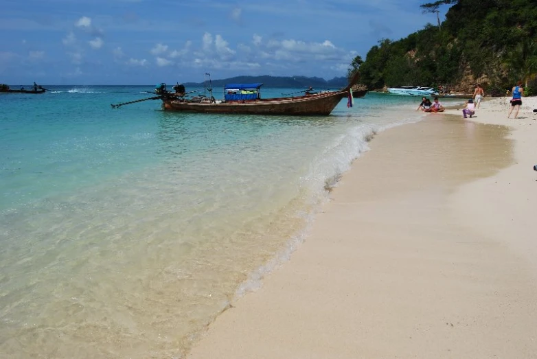 people sit on the sand and watch boats on the beach