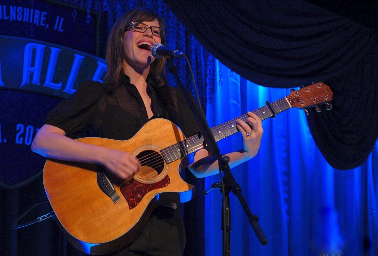 a person singing into a microphone while holding a guitar