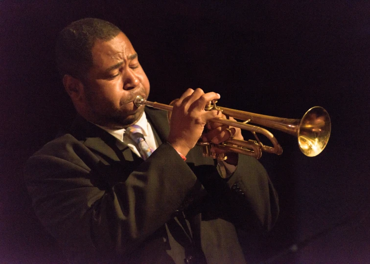 the man is playing his trumpet in the dark