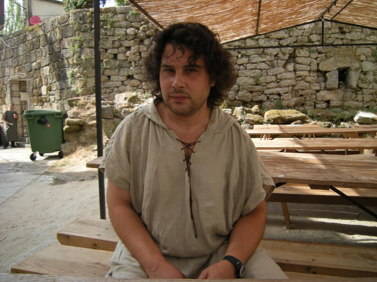 a man with a beard is sitting underneath a brown umbrella