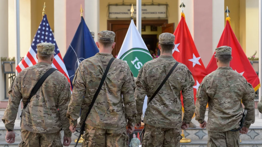 several soldiers are walking in line by some flags