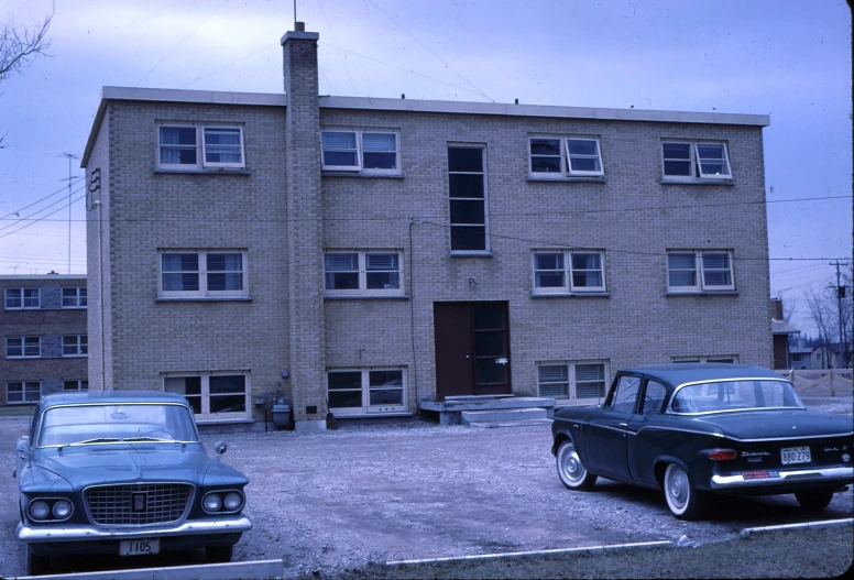 two old fashioned cars sitting outside of a large building