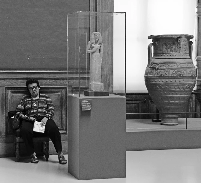 a man sitting in front of a large vase