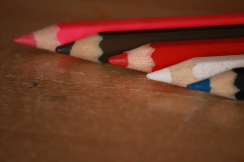 close up of colored pencils lined up on wooden surface