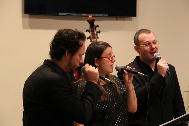 three people with a microphone standing up and looking at someone