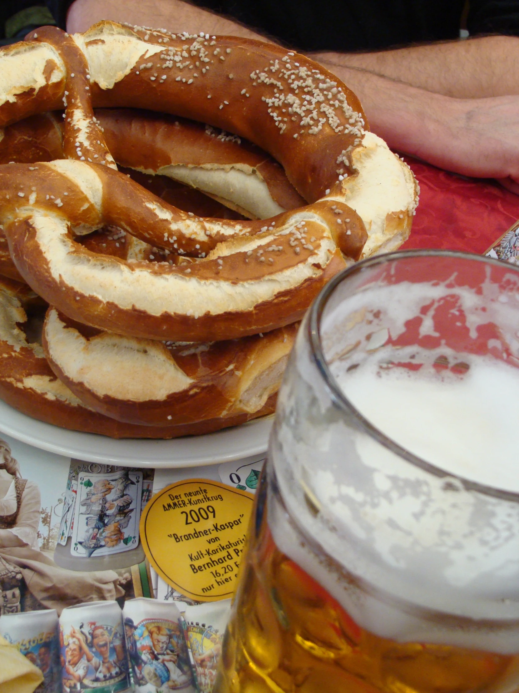 a plate full of pretzel rolls next to a glass of beer