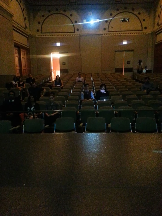 people sit in an auditorium while others sit and watch