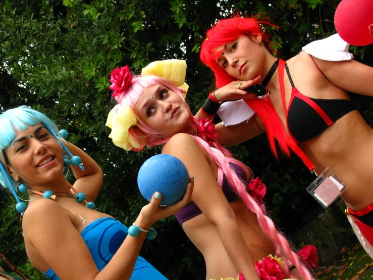 three women in costume with colorful hair playing a game of tugo