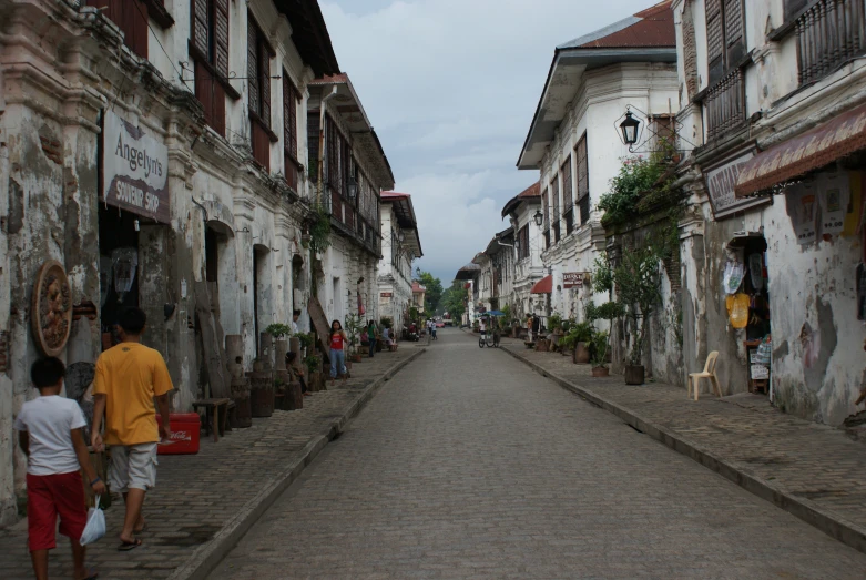 people walk down an alleyway in an old city