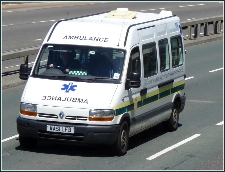 an ambulance car driving down the street with an emergency sign on the roof
