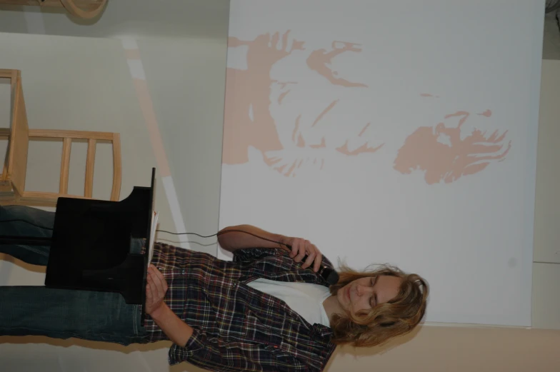 a woman talking on a microphone in front of a picture