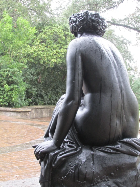 there is a black sculpture of a woman sitting on a rock