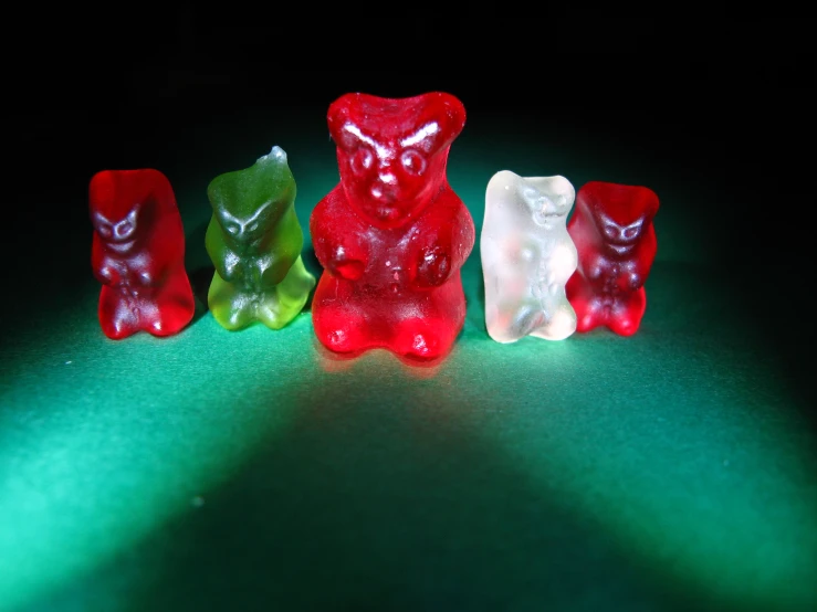 four gummy bears are in the dark with their shadows on the ground