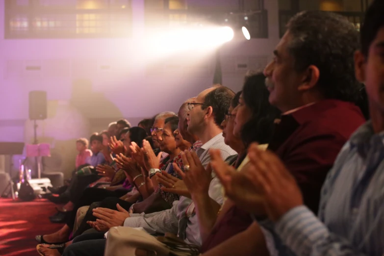 a crowd is clapping as they watch soing on television