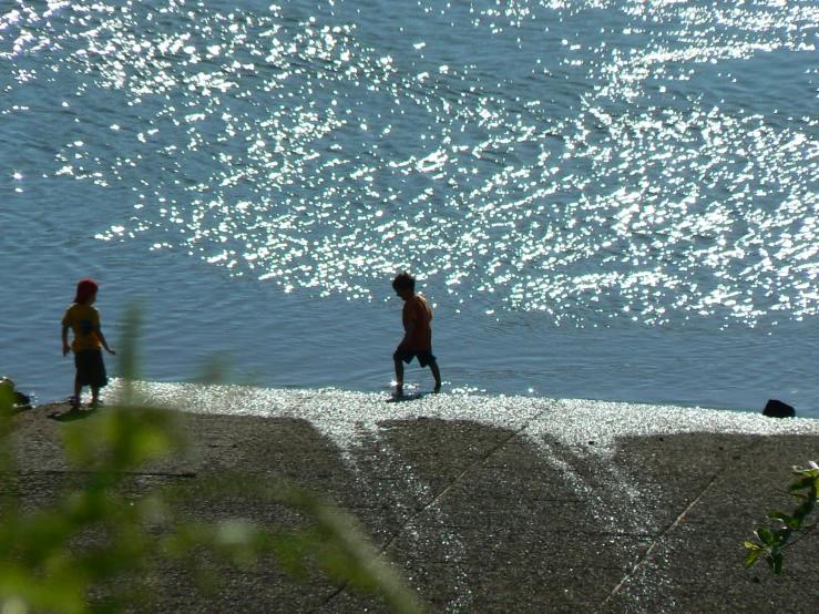 two people are walking next to the beach